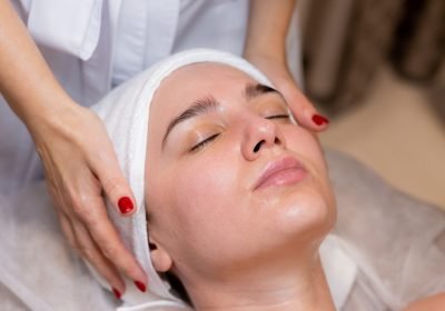 A young beautiful girl lies on the beautician's table and receives procedures, a light facial massage. Woman takes care of herself, enjoys massage